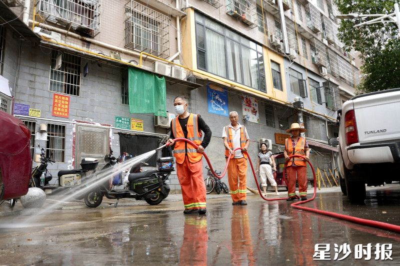 长沙县松雅小区背街小巷里，环卫工人手持高压水枪冲刷着地面污渍，水声此起彼伏。均为杨欣雨 摄