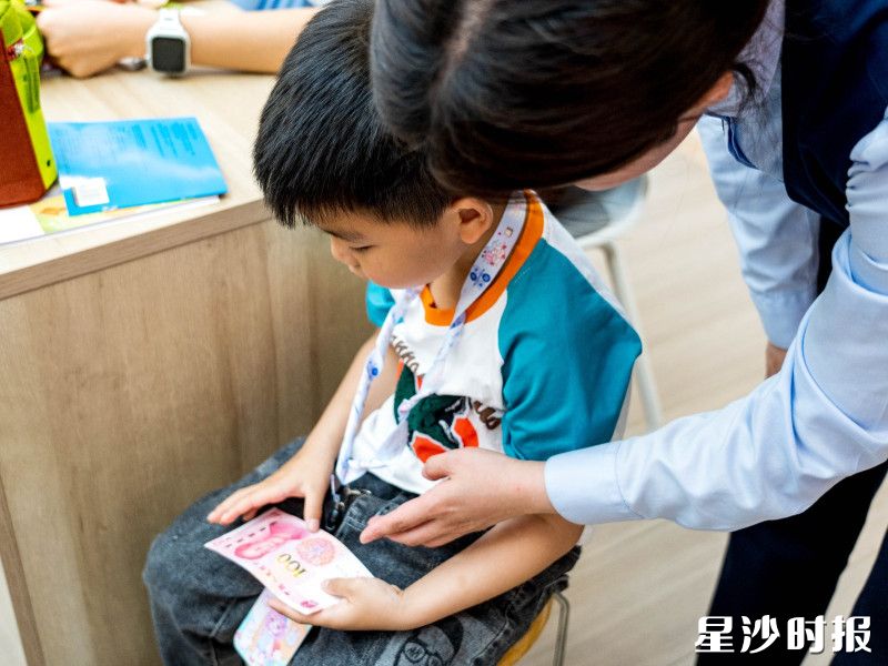 工作人员引导孩子用手指触摸纸币凹凸纹路。 工作人员引导孩子用手指触摸纸币凹凸纹路。