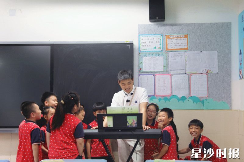 下课时间,学生围在尹碧文身边,听他唱歌弹琴。均为文雅丽摄