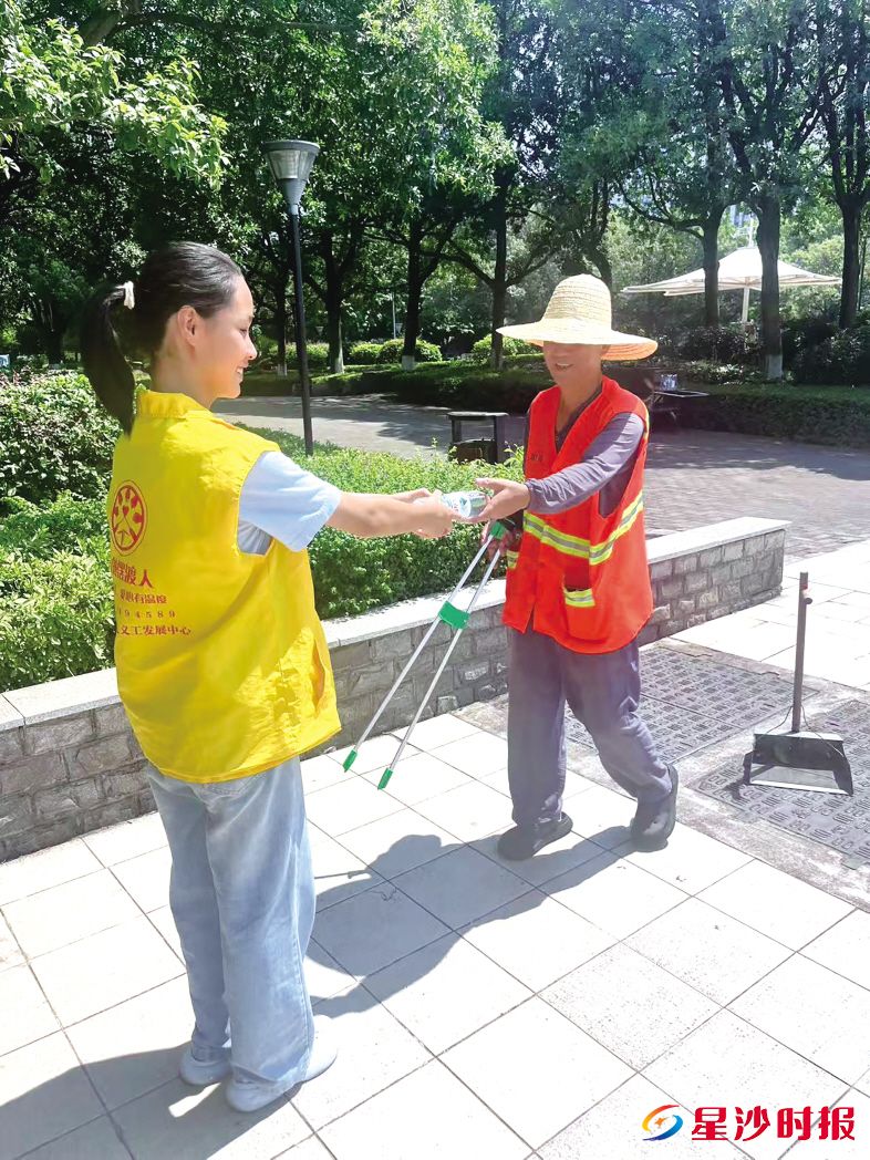 　　志愿者将爱心物资送到高温作业者手中。长沙县爱的摆渡人义工发展中心供图
