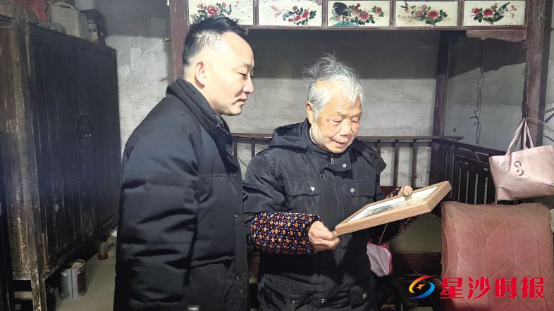 　　杨建鸿（右）从余瑶（左）的手中接过一张精心装裱的照片。安沙镇供图