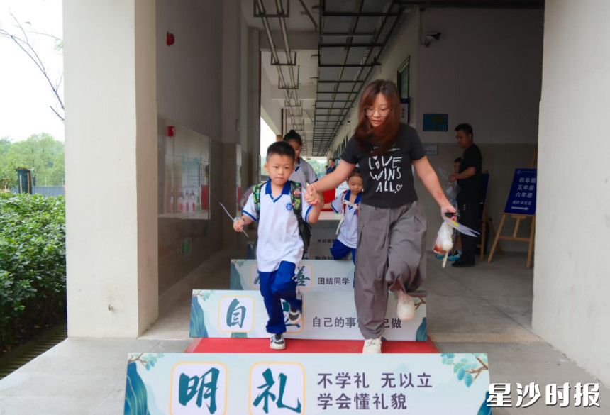 在南雅远航实验学校,家长牵起学生的手,一同迈步跨过成长阶梯,踏过明礼自立的成长之门。